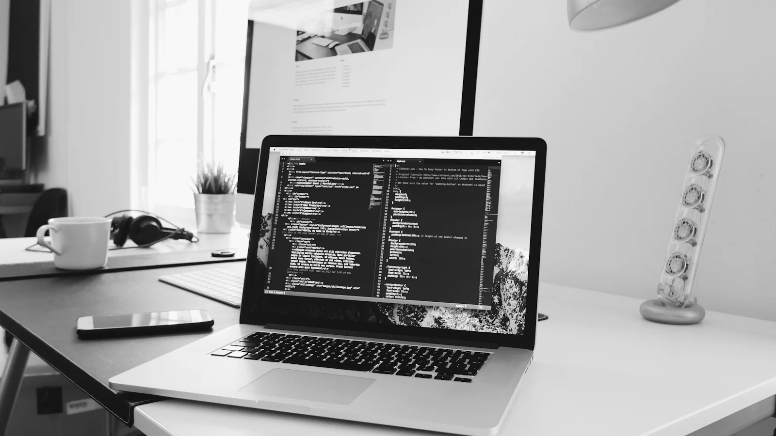 Una computadora portátil muestra código en un escritorio de trabajo.