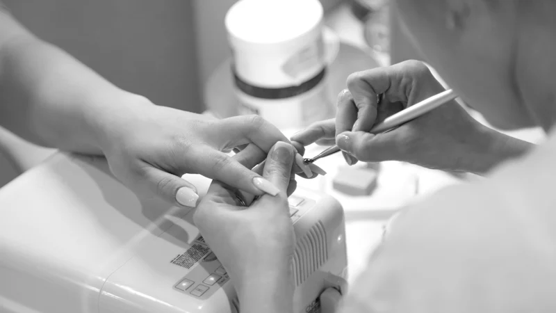 Una manicurista trabaja las uñas de una clienta en un salón de uñas.